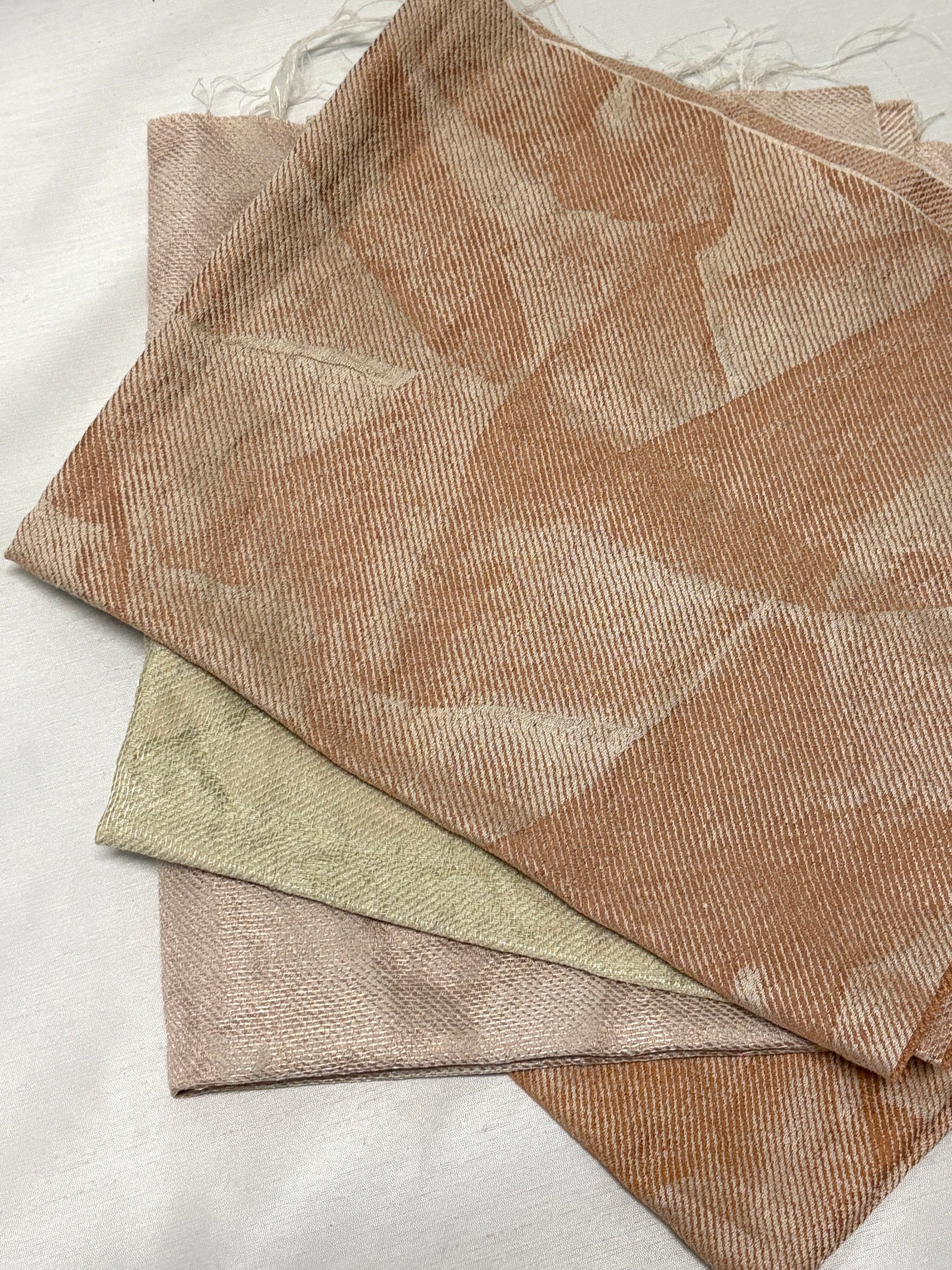 Detailed view of layered fabric swatches in soft neutral tones.