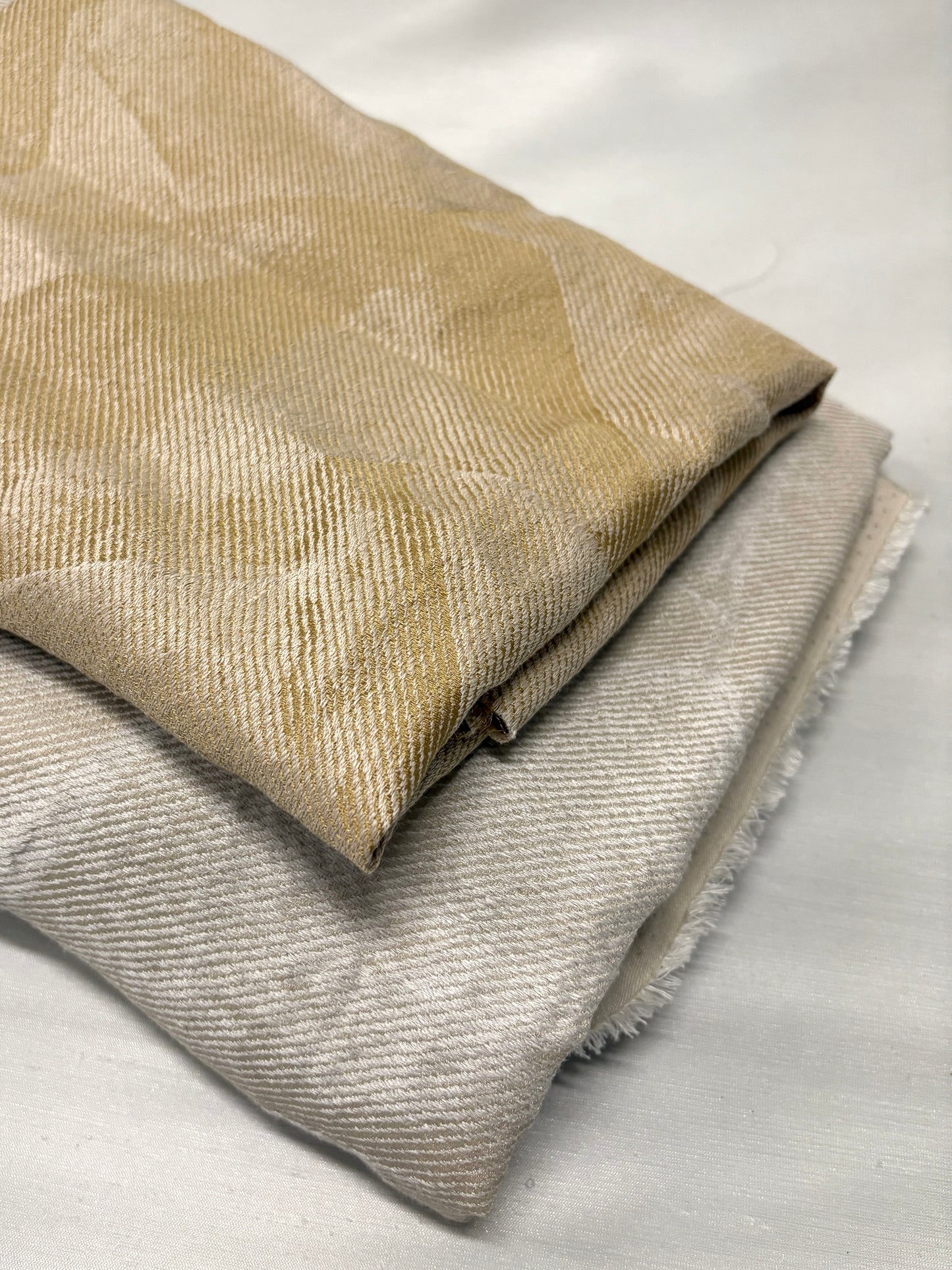 Close-up of folded neutral fabrics with subtle woven texture and pattern.
