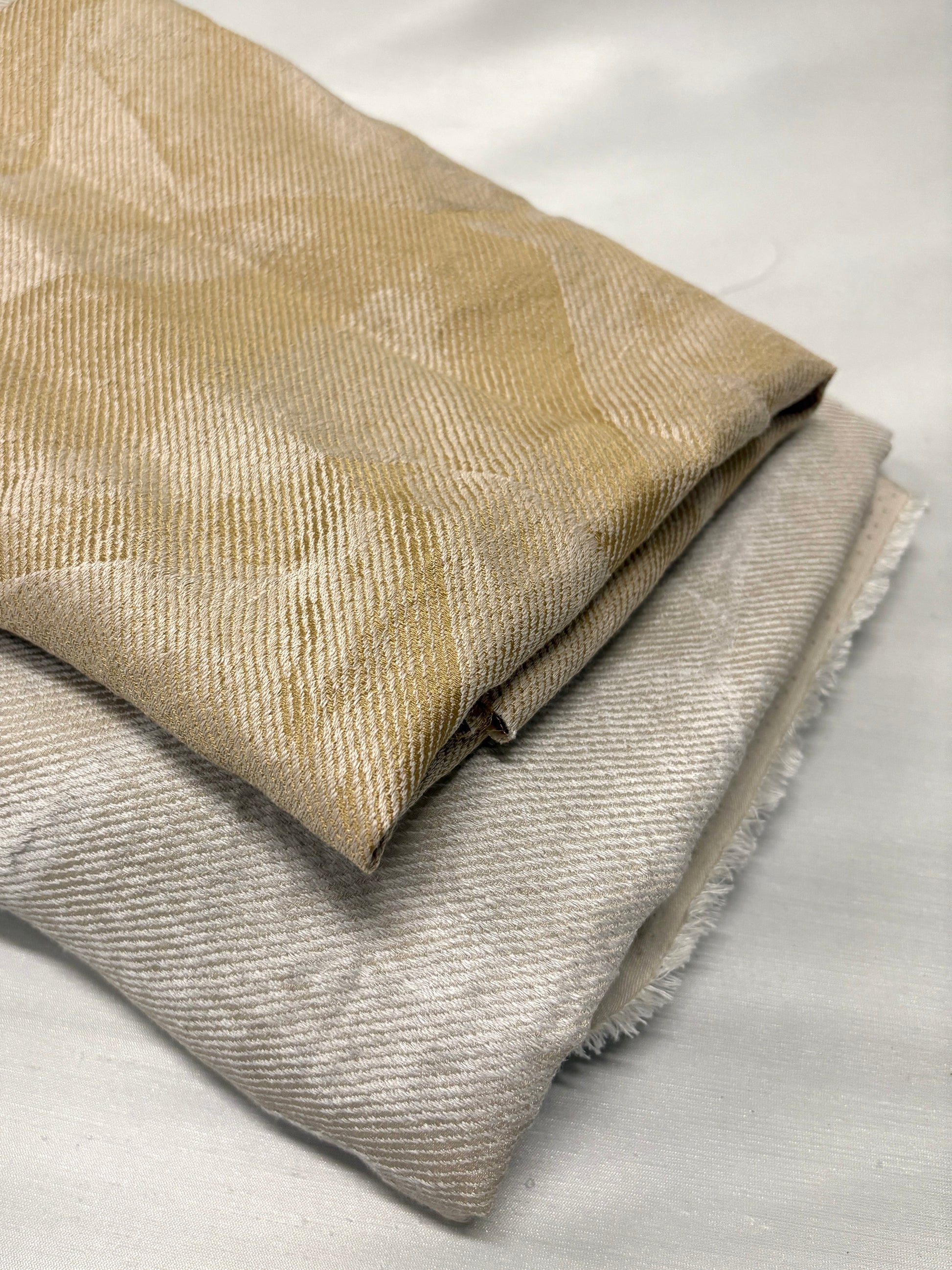 Close-up of folded neutral fabrics with subtle woven texture and pattern.