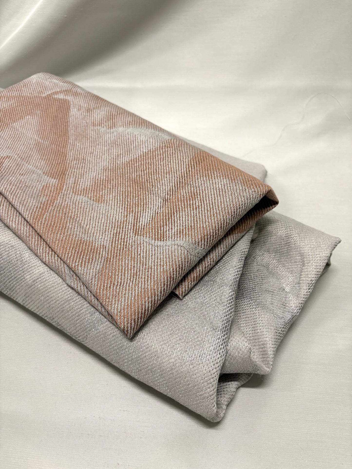 Close-up of folded neutral fabrics with subtle pattern and woven texture.