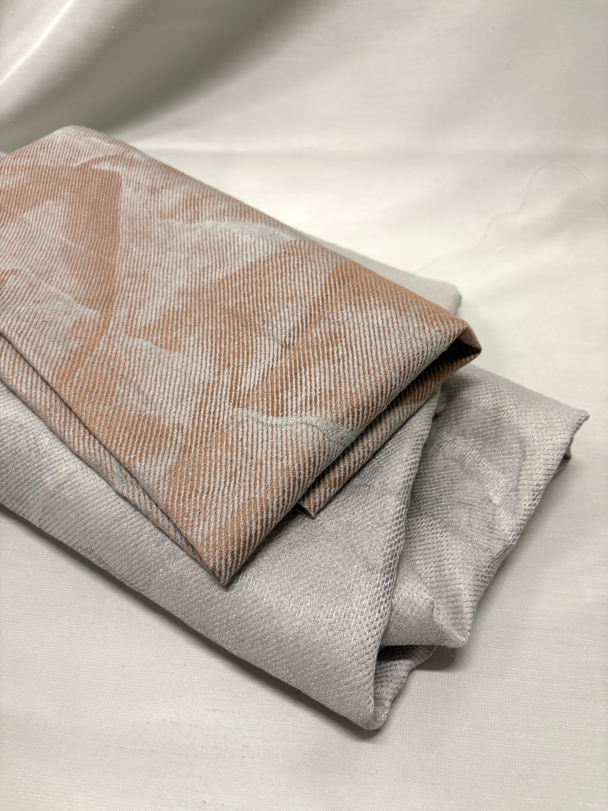 Close-up of folded neutral fabrics with subtle pattern and woven texture.