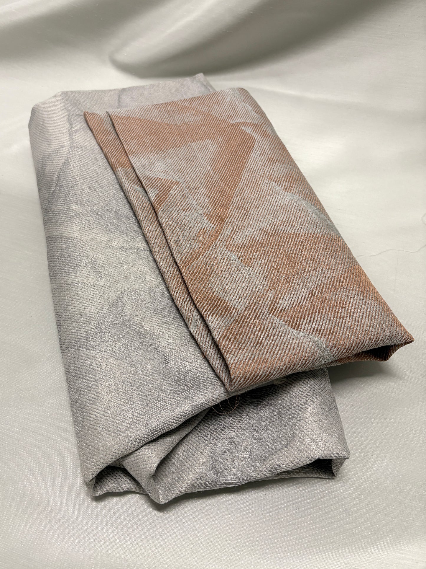 Detailed view of folded neutral fabrics with a soft woven pattern.