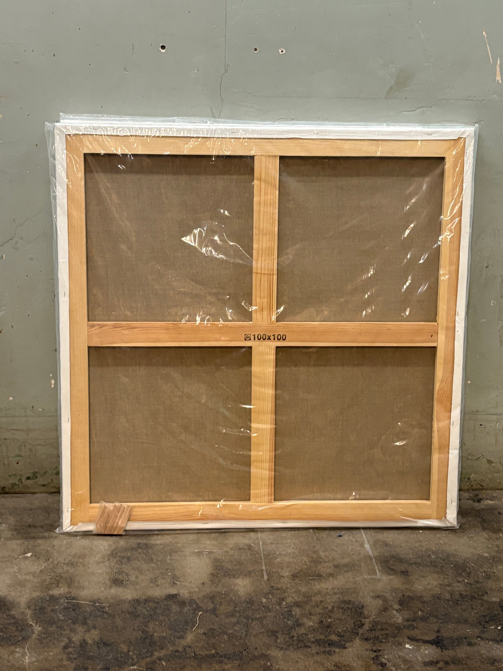 A back of the square canvas, the wooden frame is cross-shaped, covered with plastic film