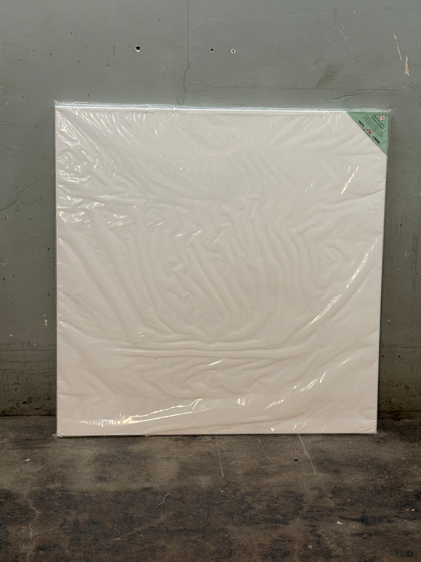 A square white canvas covered with plastic film