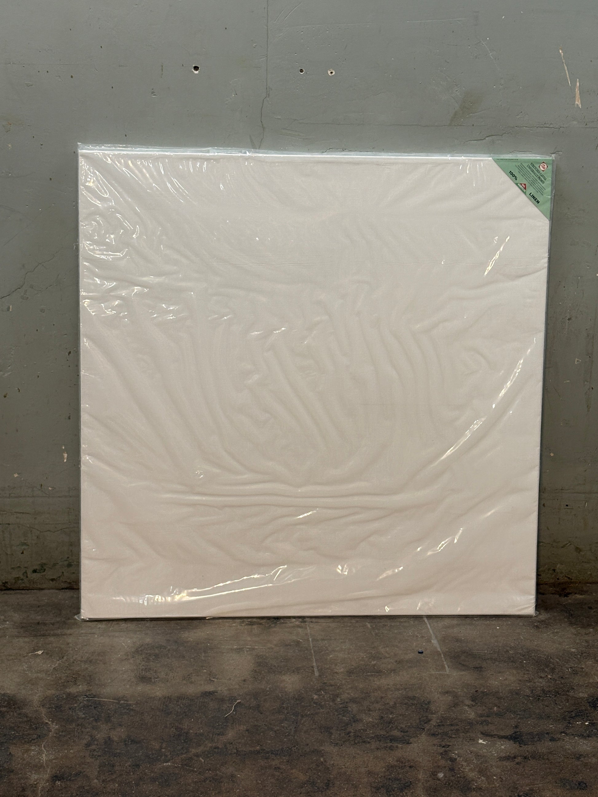 A square white canvas covered with plastic film