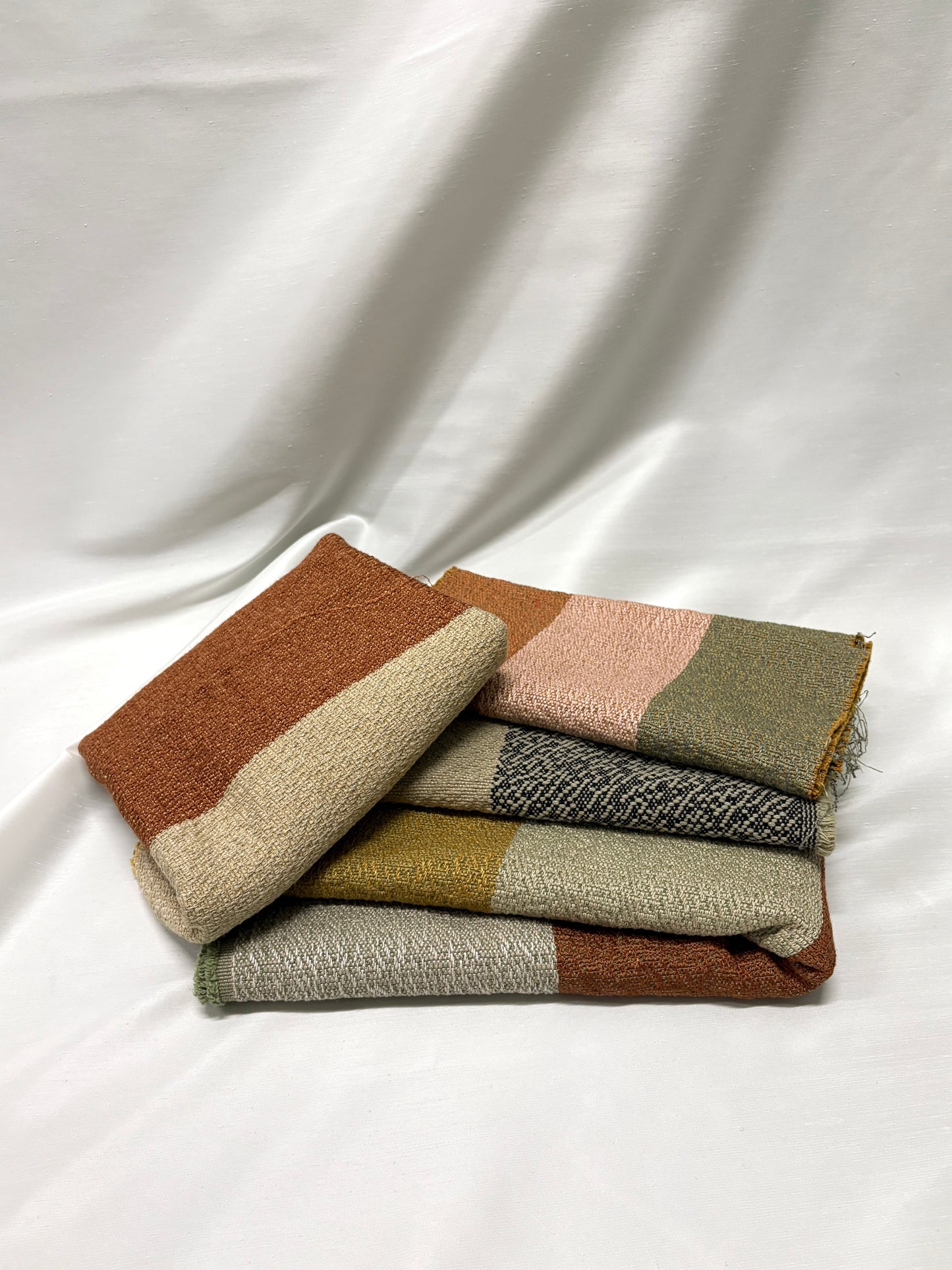 Stacked colour-block fabric swatches in warm earthy tones on a light background.