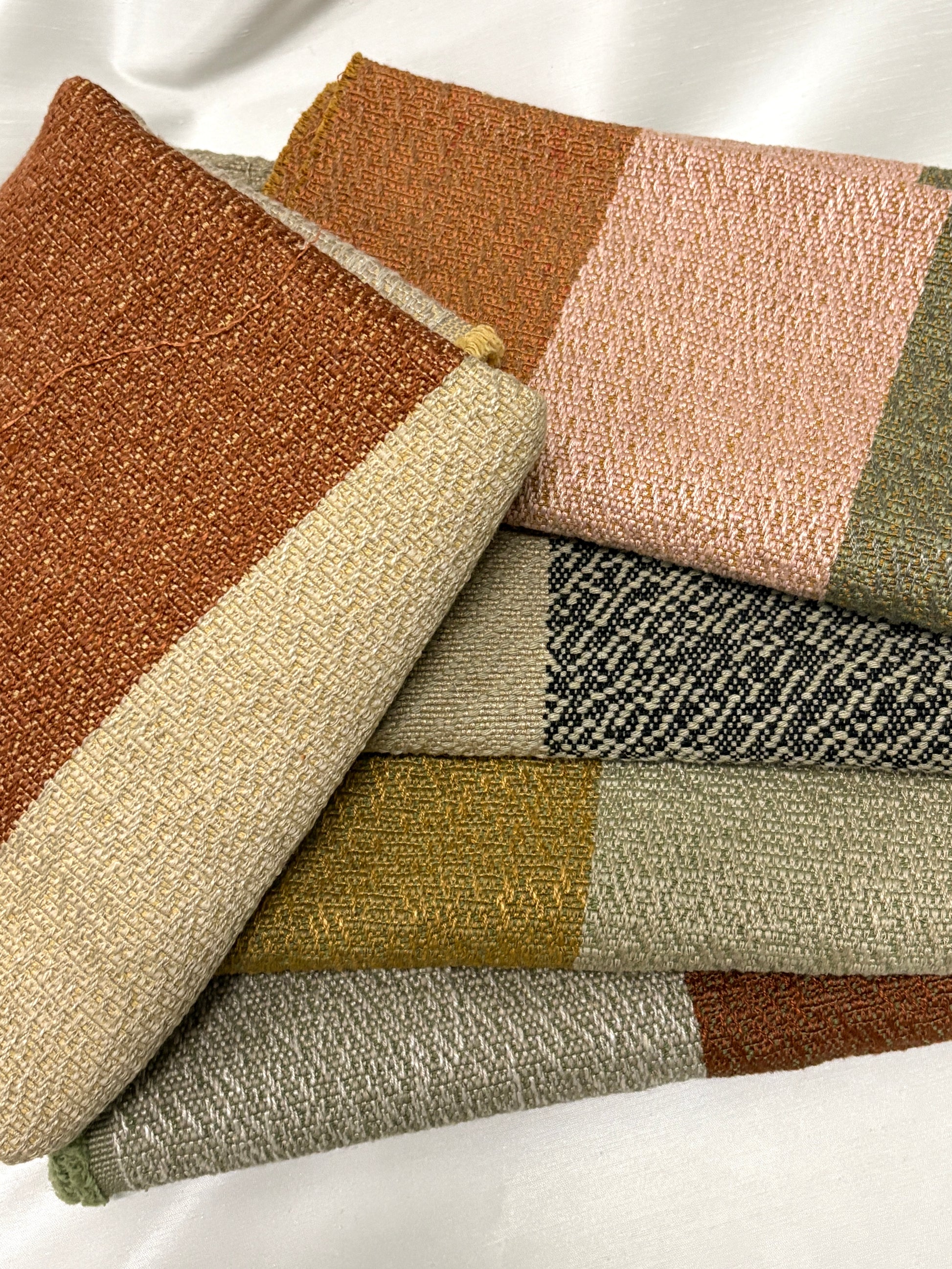 Close-up of stacked colour-block fabric swatches in textured earthy tones.