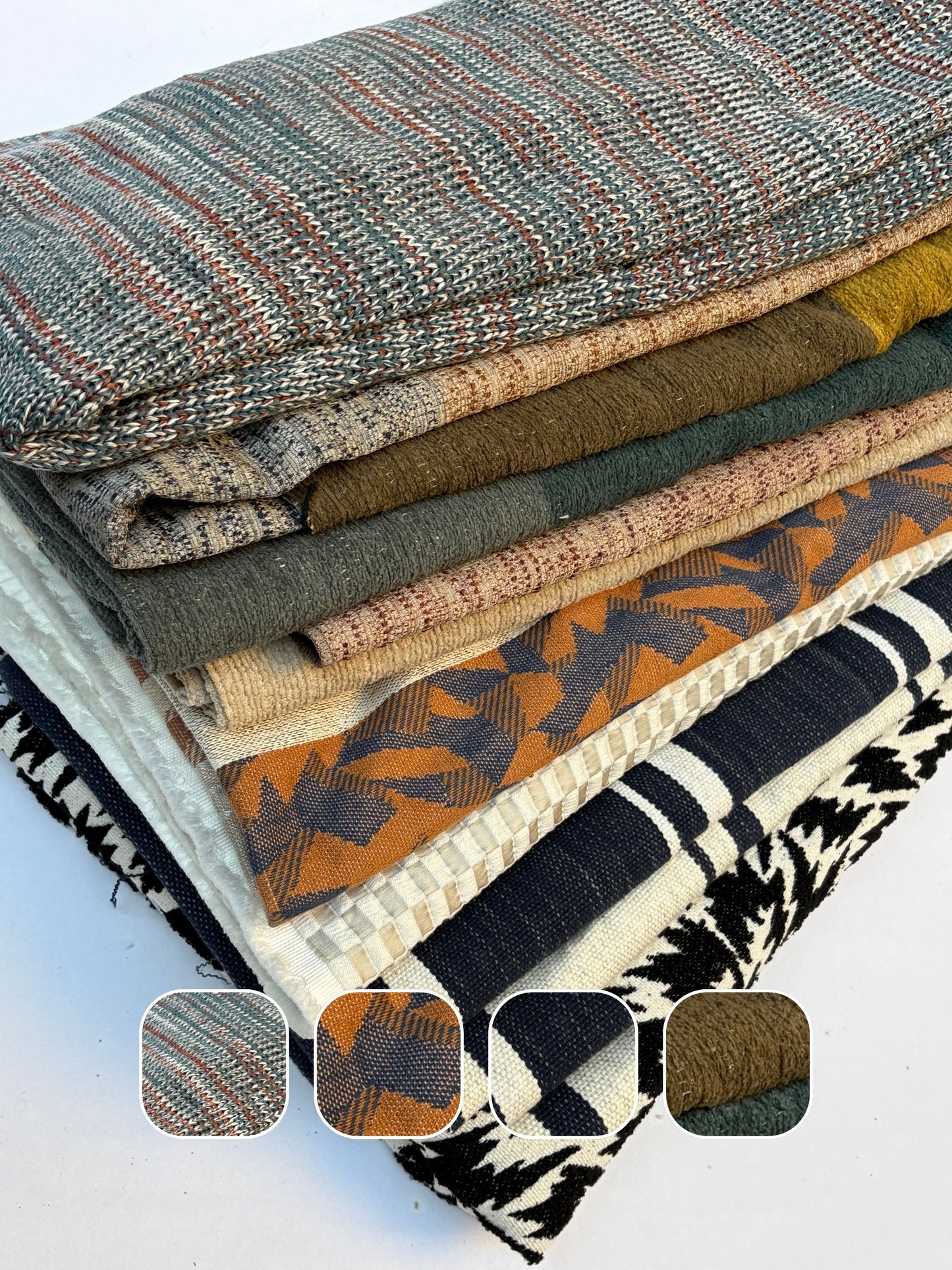 Stack of heavyweight textured fabric pieces with assorted woven patterns on white.
