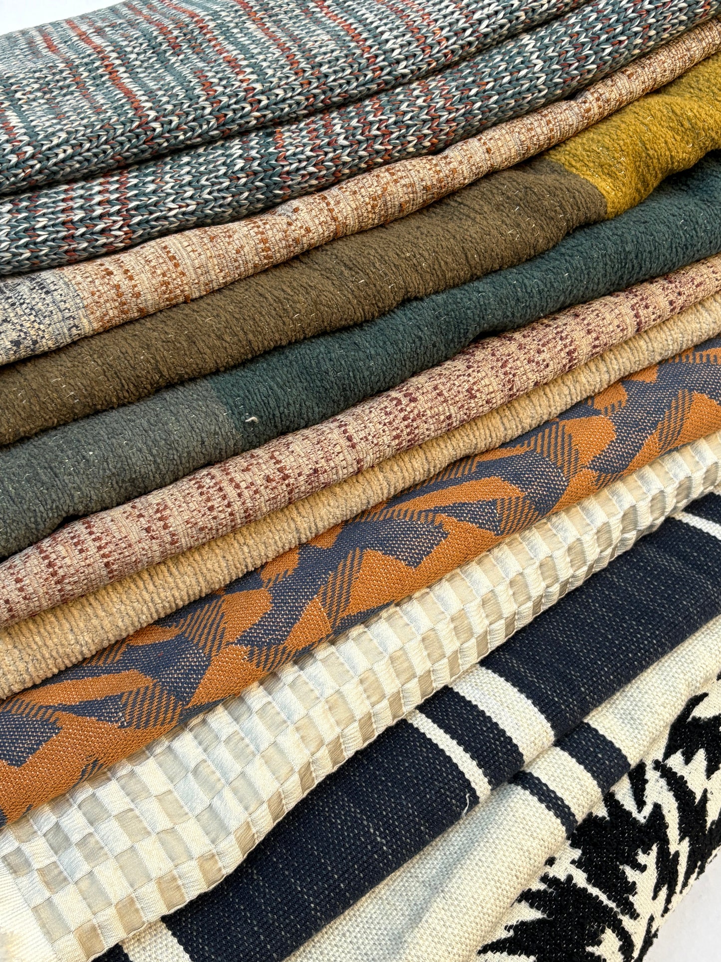 Close-up of stack of folded, textured variety of patterns fabric 