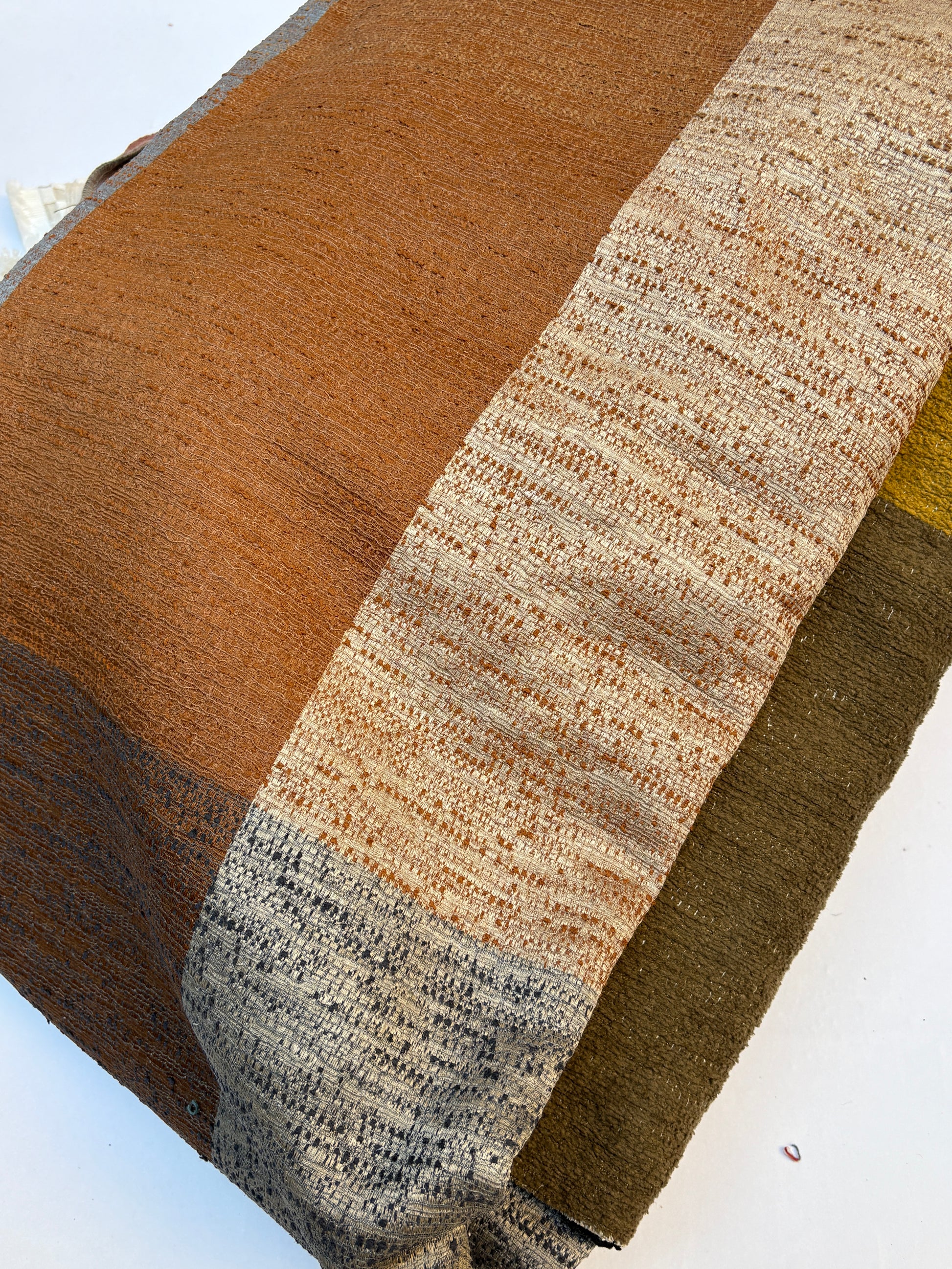 Close-up of a textured fabric with stripe brown, beige, and green colours 