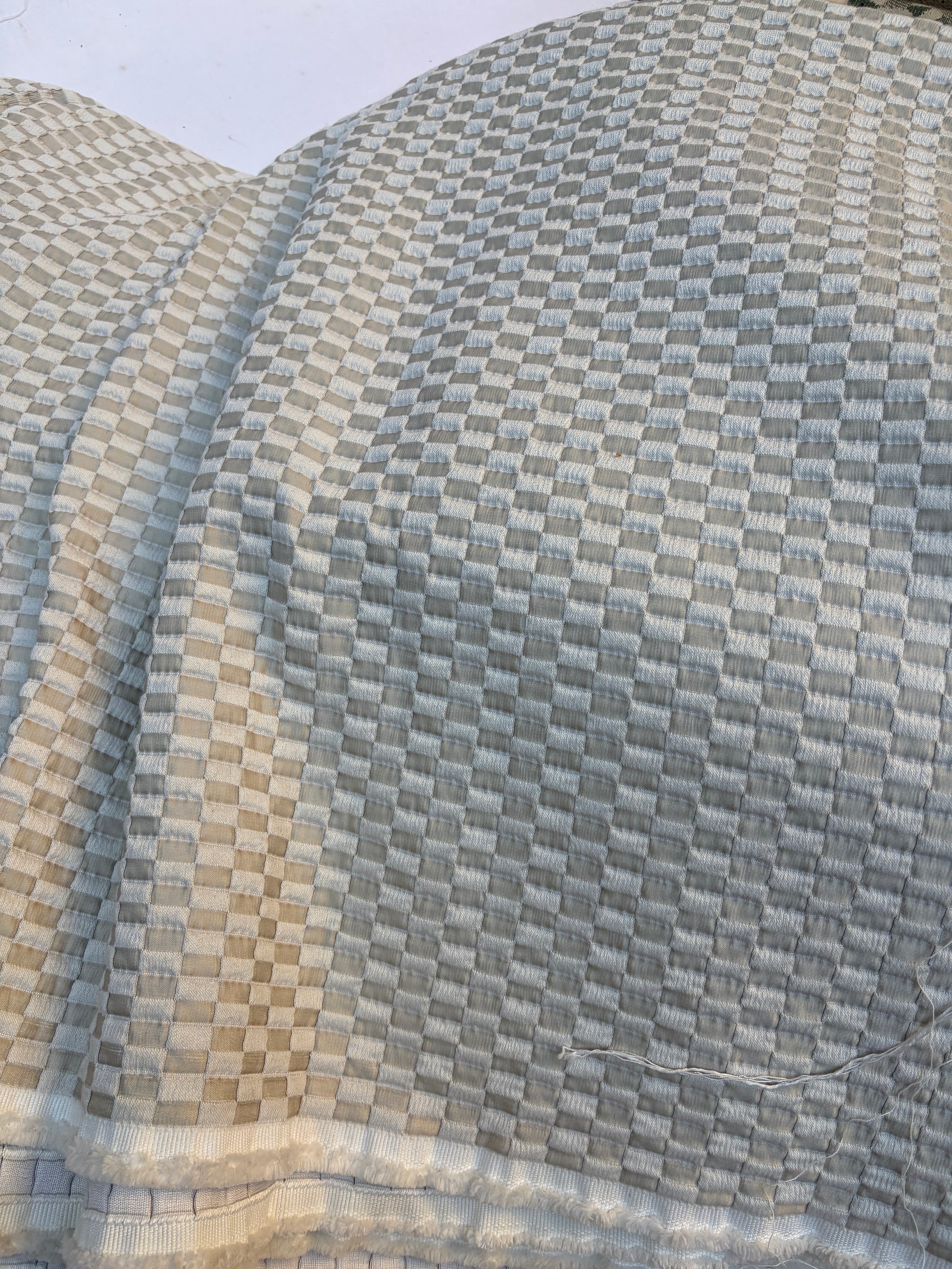 Close-up of textured fabric with a light grey and light blue checkered pattern 