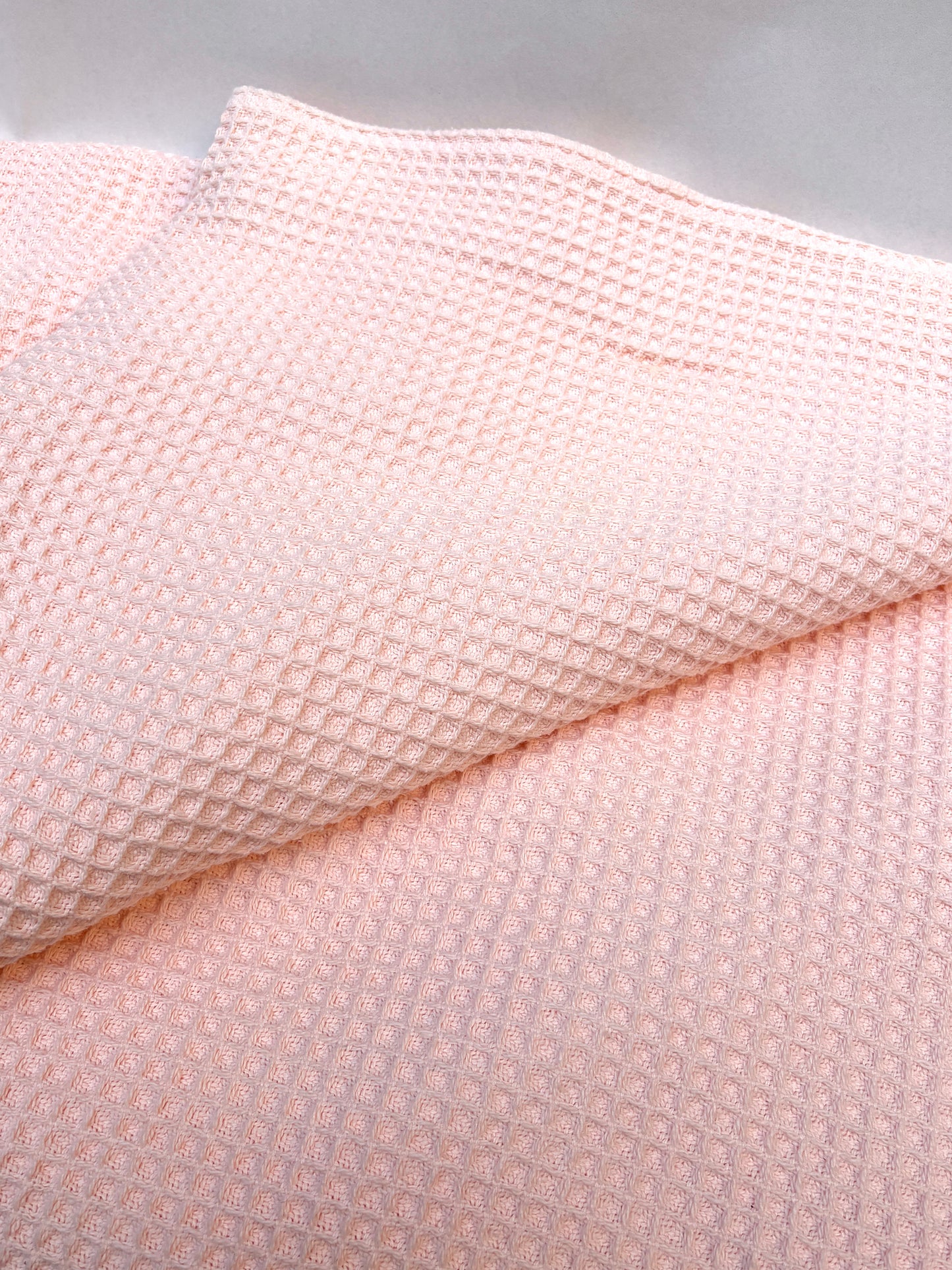 Close-up of layered pink waffle-textured fabric pieces on a white background.