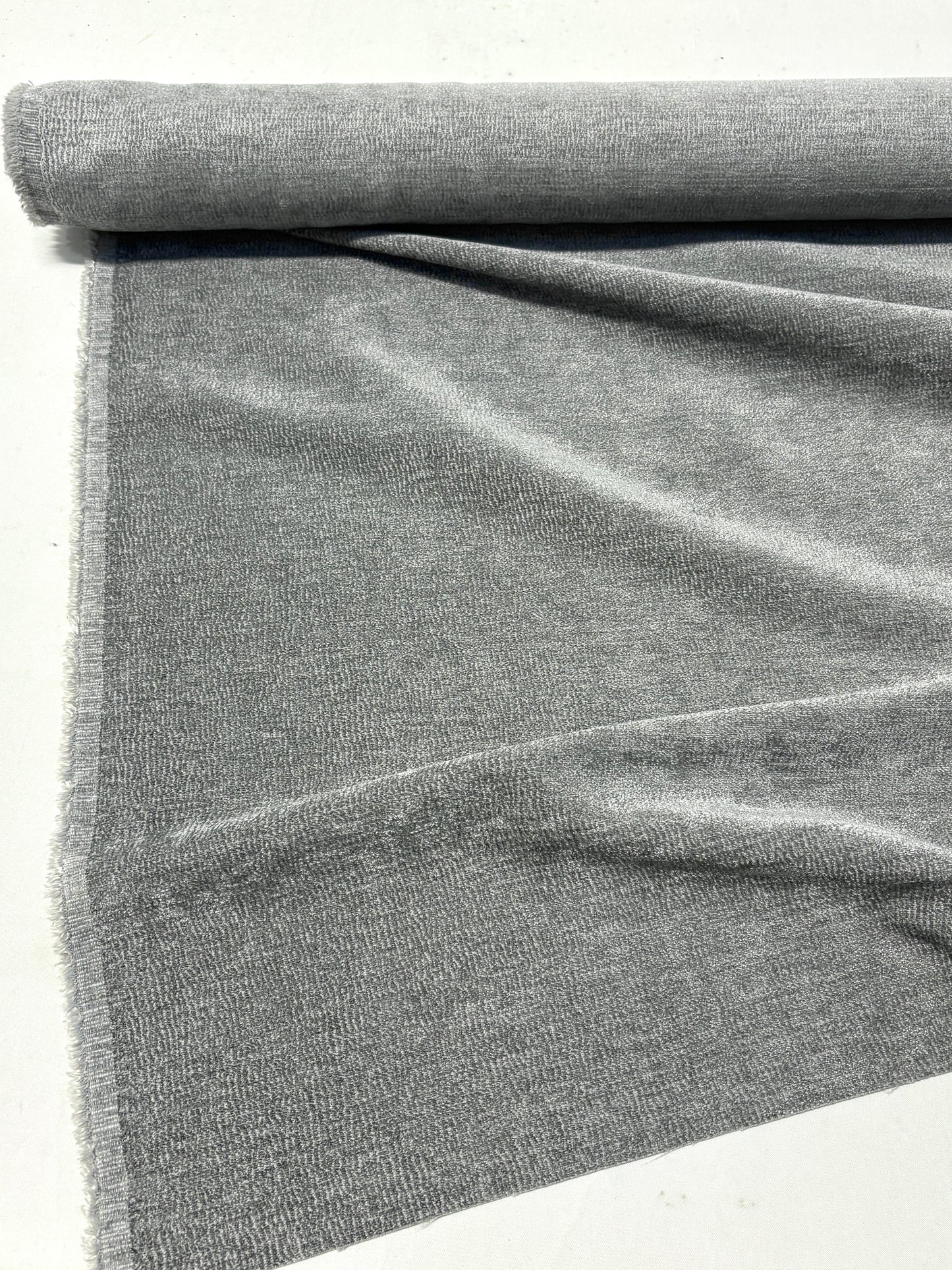 Rolled gray textured weave velvet fabric, partially unfolded 