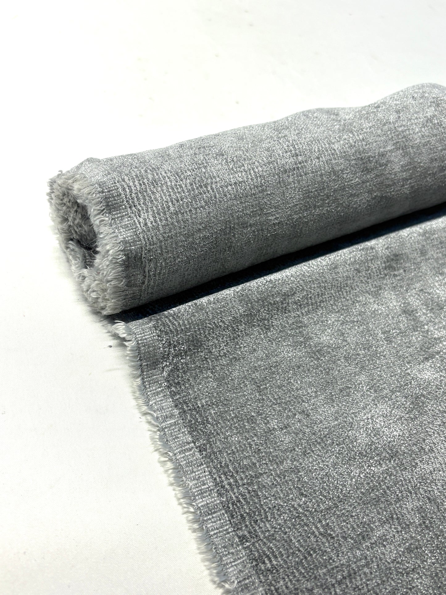 Close-up of rolled grey textured weave velvet fabric from its edge