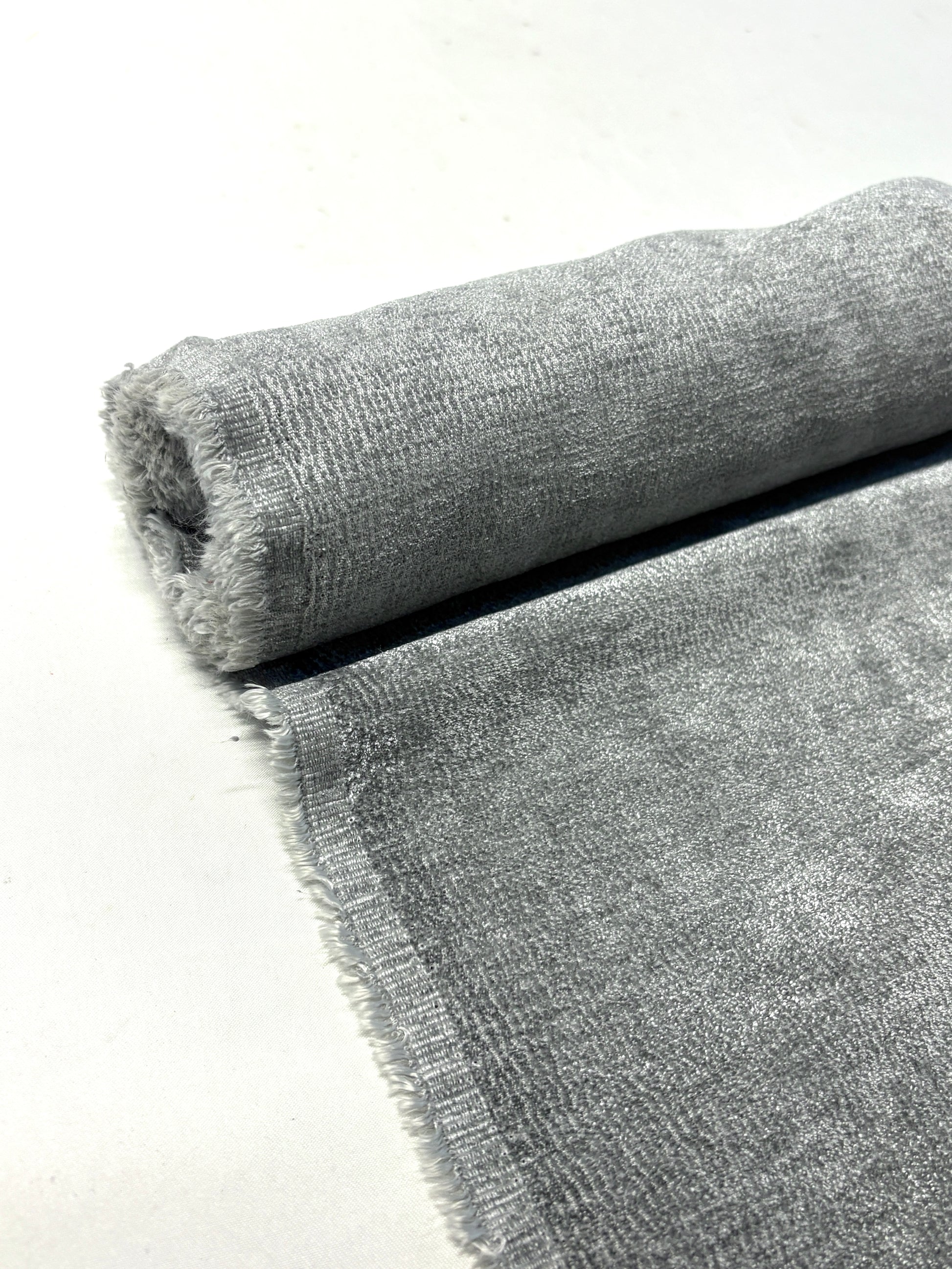 Close-up of rolled grey textured weave velvet fabric from its edge