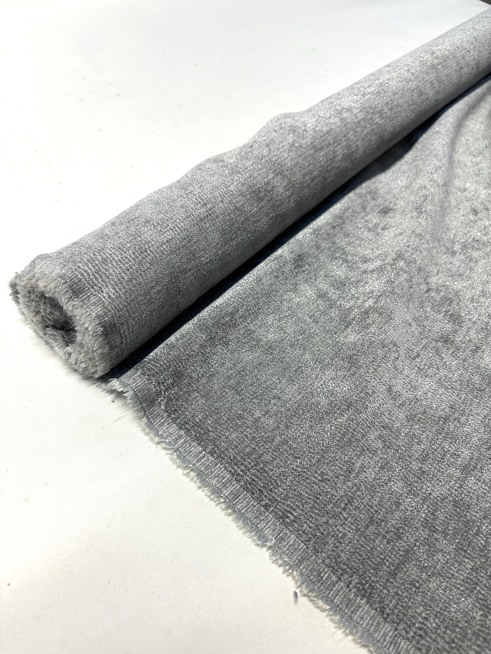 Close-up of rolled grey textured weave velvet fabric from its edge