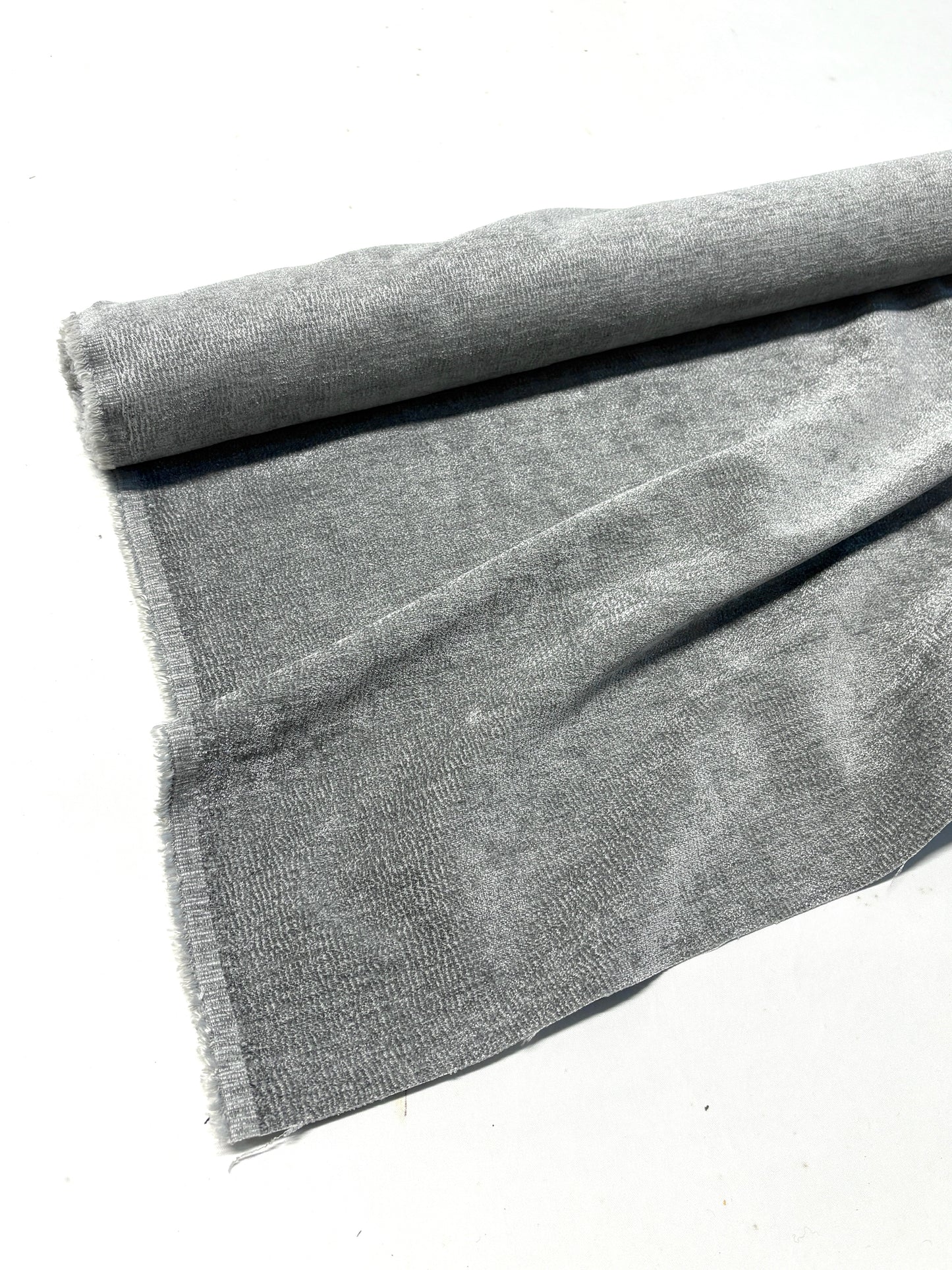 Close-up of rolled grey textured weave velvet fabric, partially unfolded