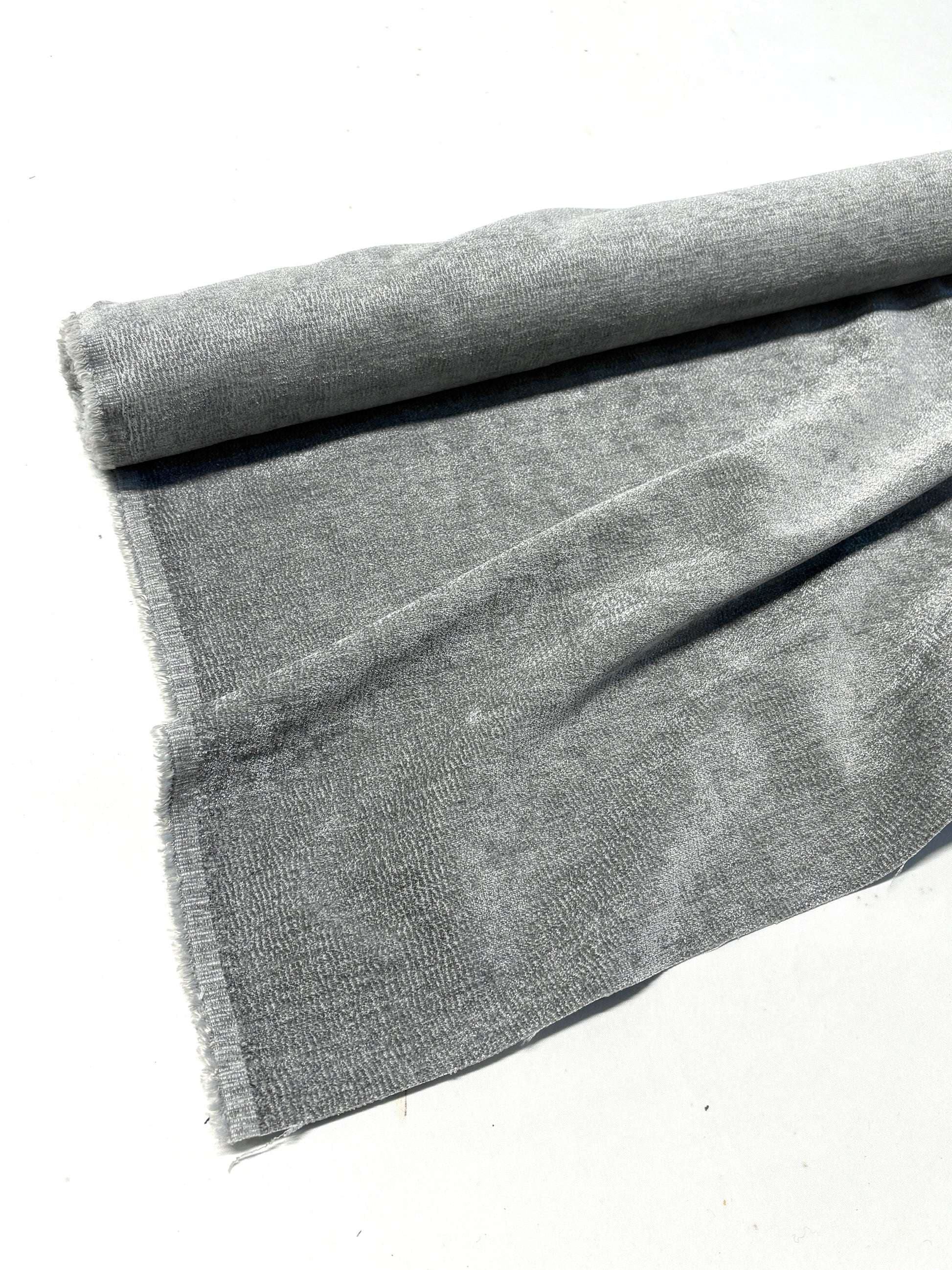 Close-up of rolled grey textured weave velvet fabric, partially unfolded