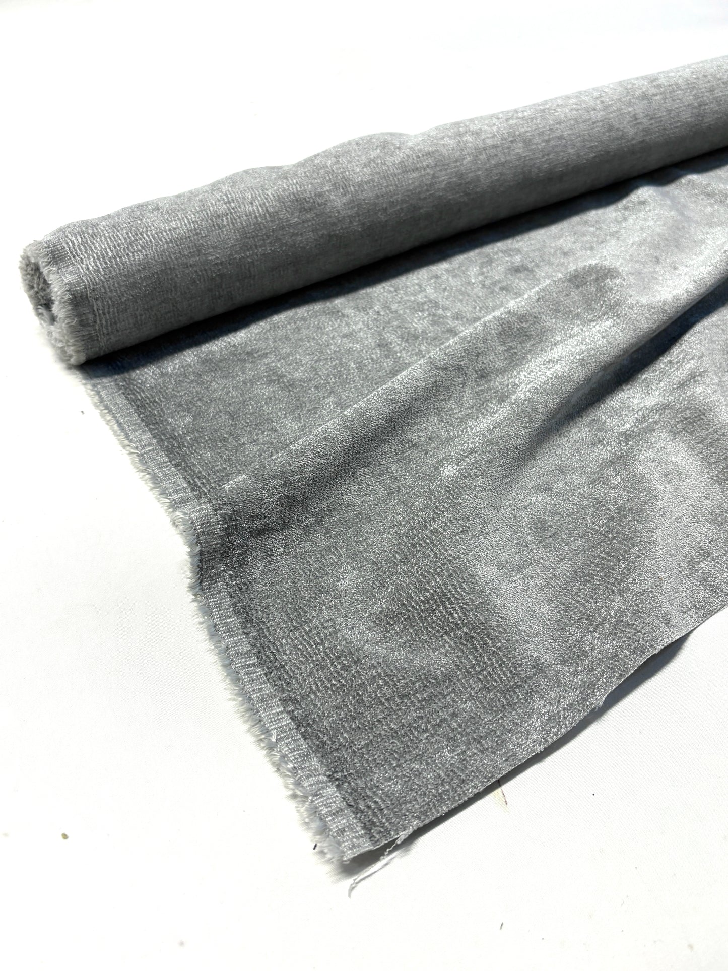 Close-up of rolled grey textured weave velvet fabric, partially unfolded