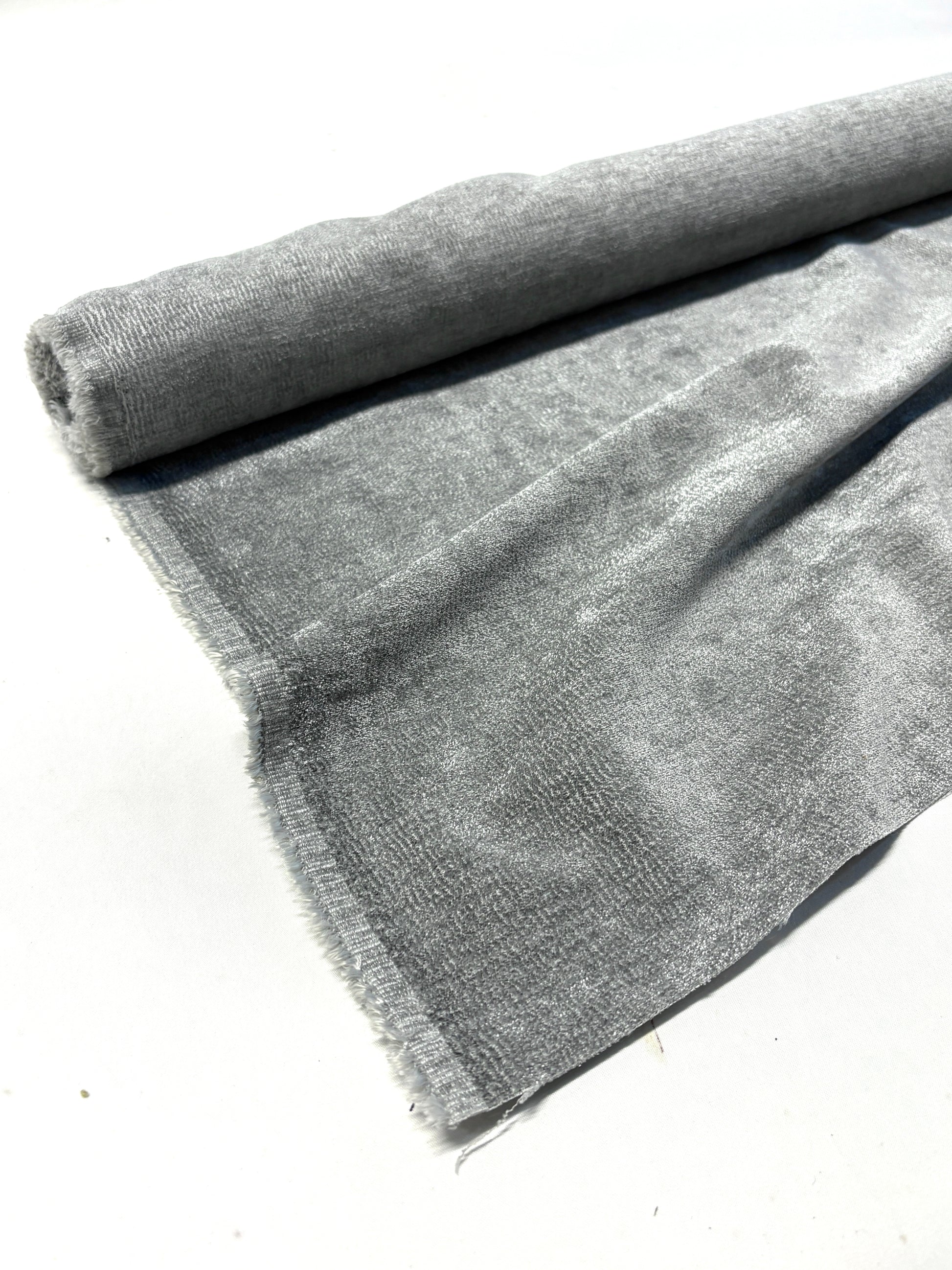 Close-up of rolled grey textured weave velvet fabric, partially unfolded
