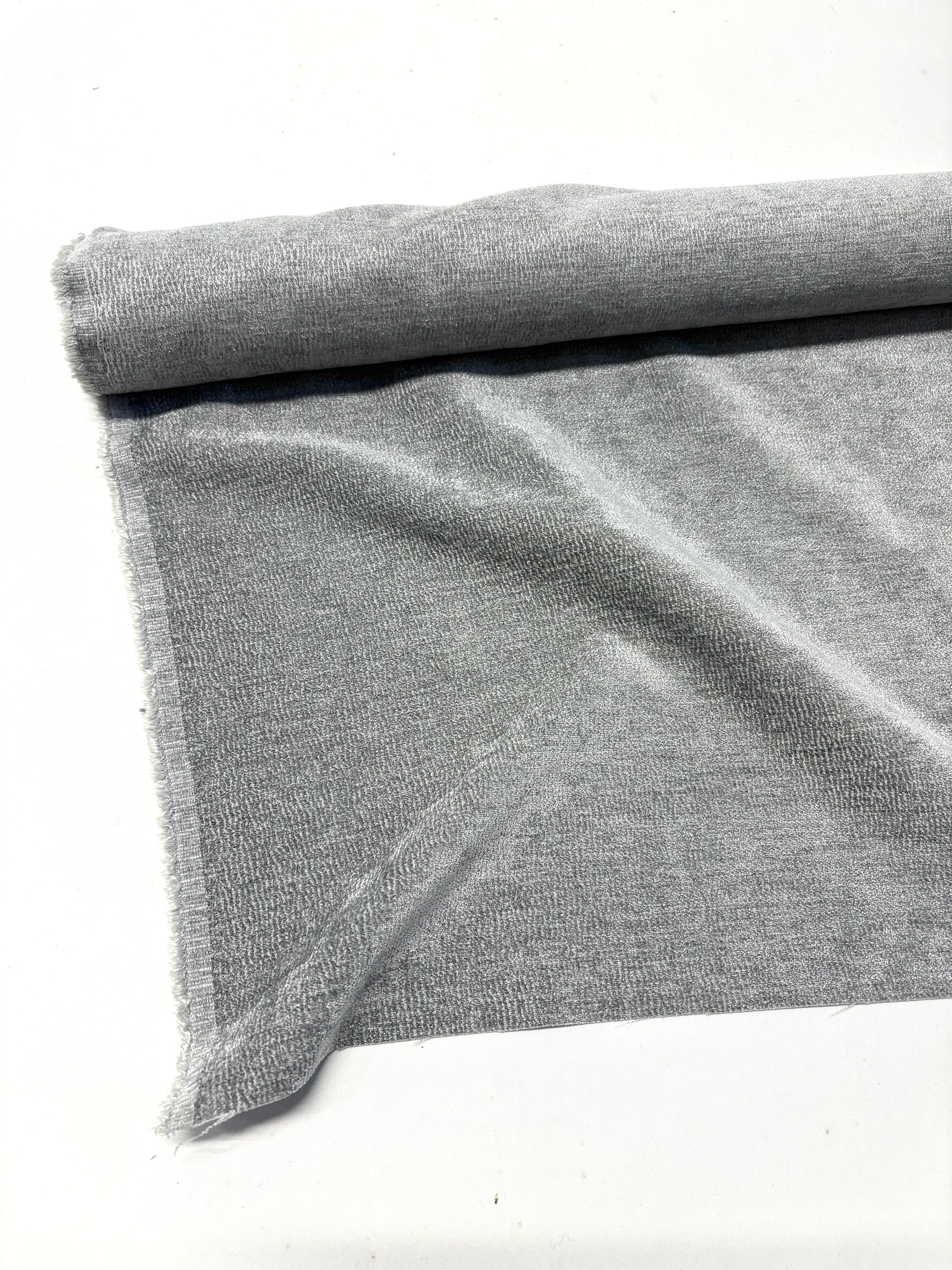 Close-up of rolled grey textured weave velvet fabric, partially unfolded