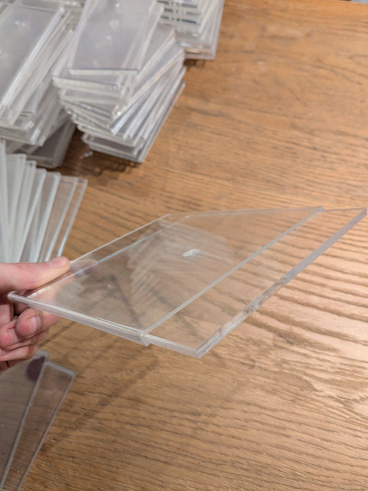 Clear plastic card held by a hand on a wooden surface with more cards stacked in the background.
