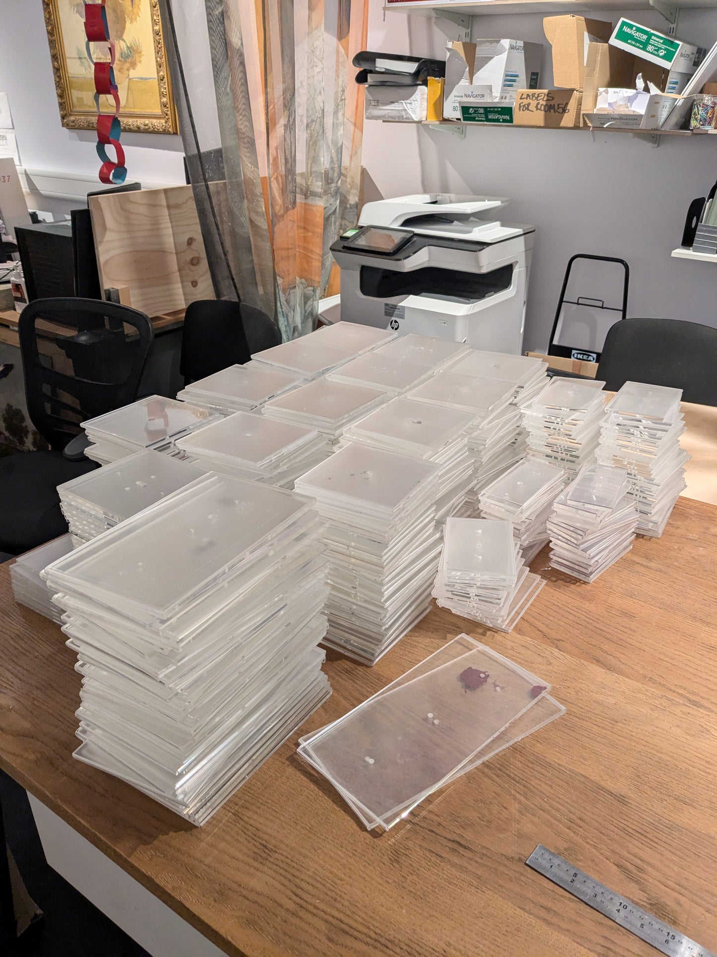 Stacks of clear plastic trays on a wooden table in an office setting.