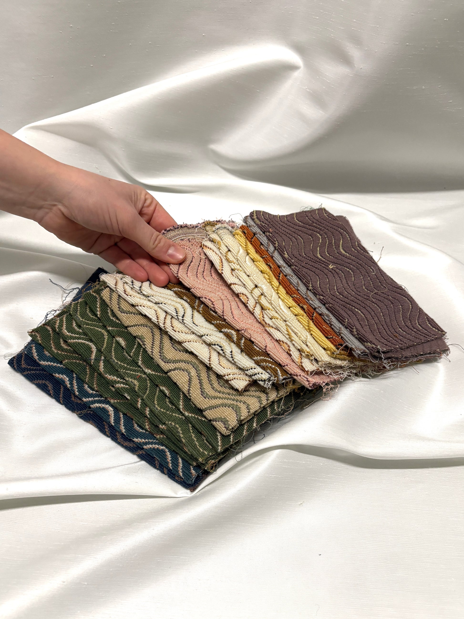 Hand holding fabric swatches on a white fabric background