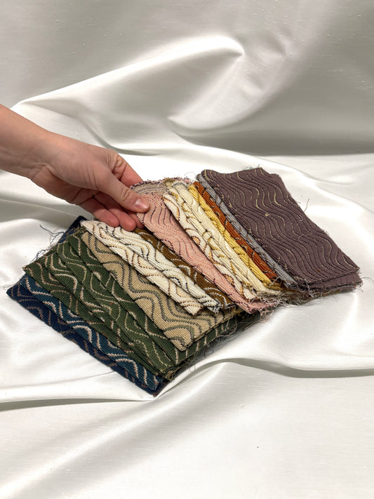 Hand holding fabric swatches on a white fabric background