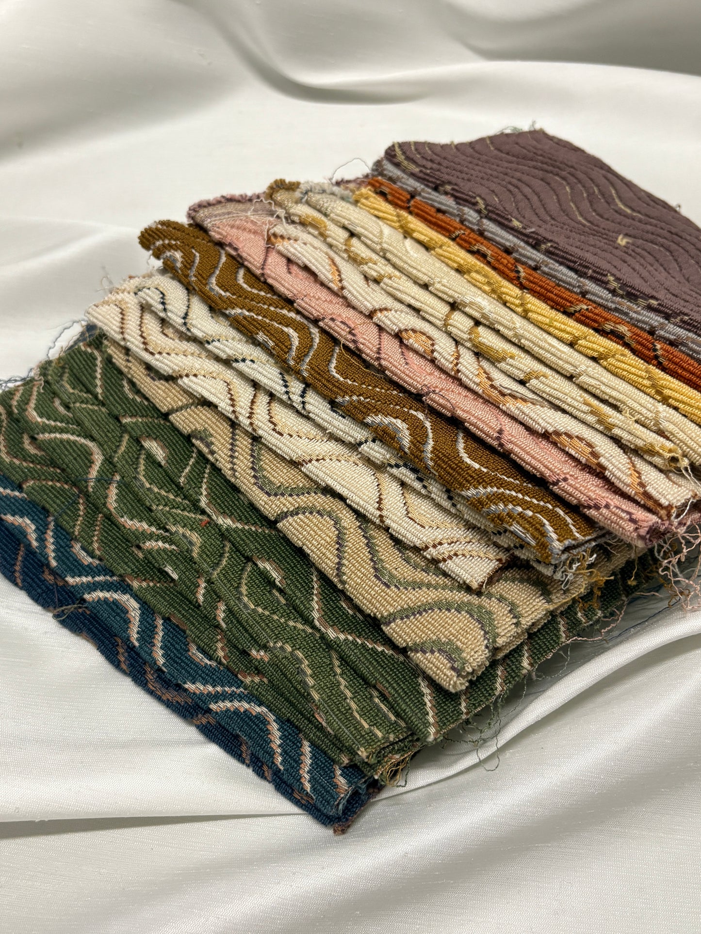 Close-up of stacked patterned fabric swatches in assorted colours and textures.