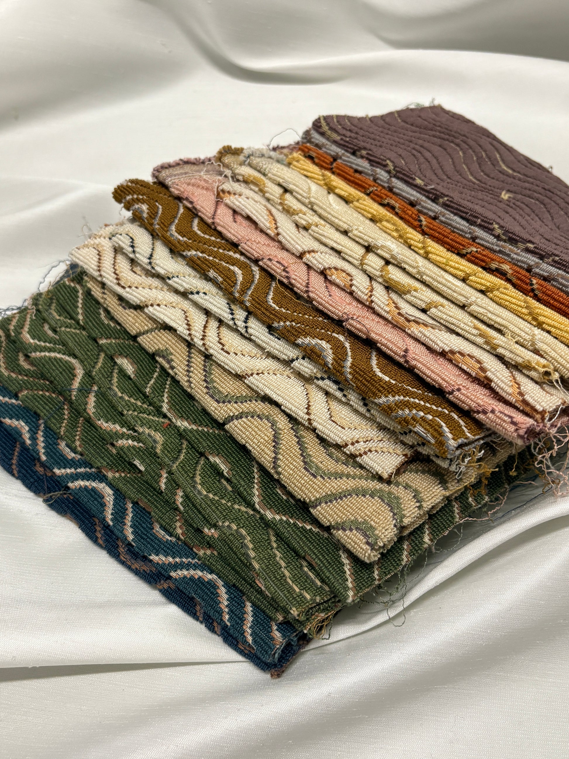 Close-up of stacked patterned fabric swatches in assorted colours and textures.