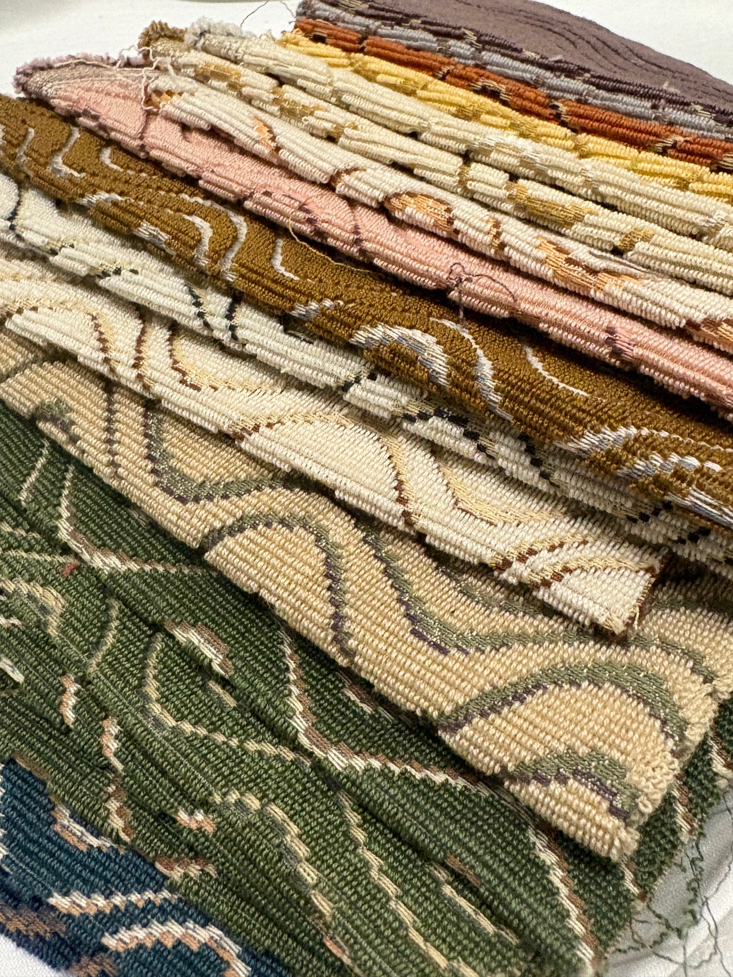 Close-up of stacked fabric swatches in varied colours and woven patterns.