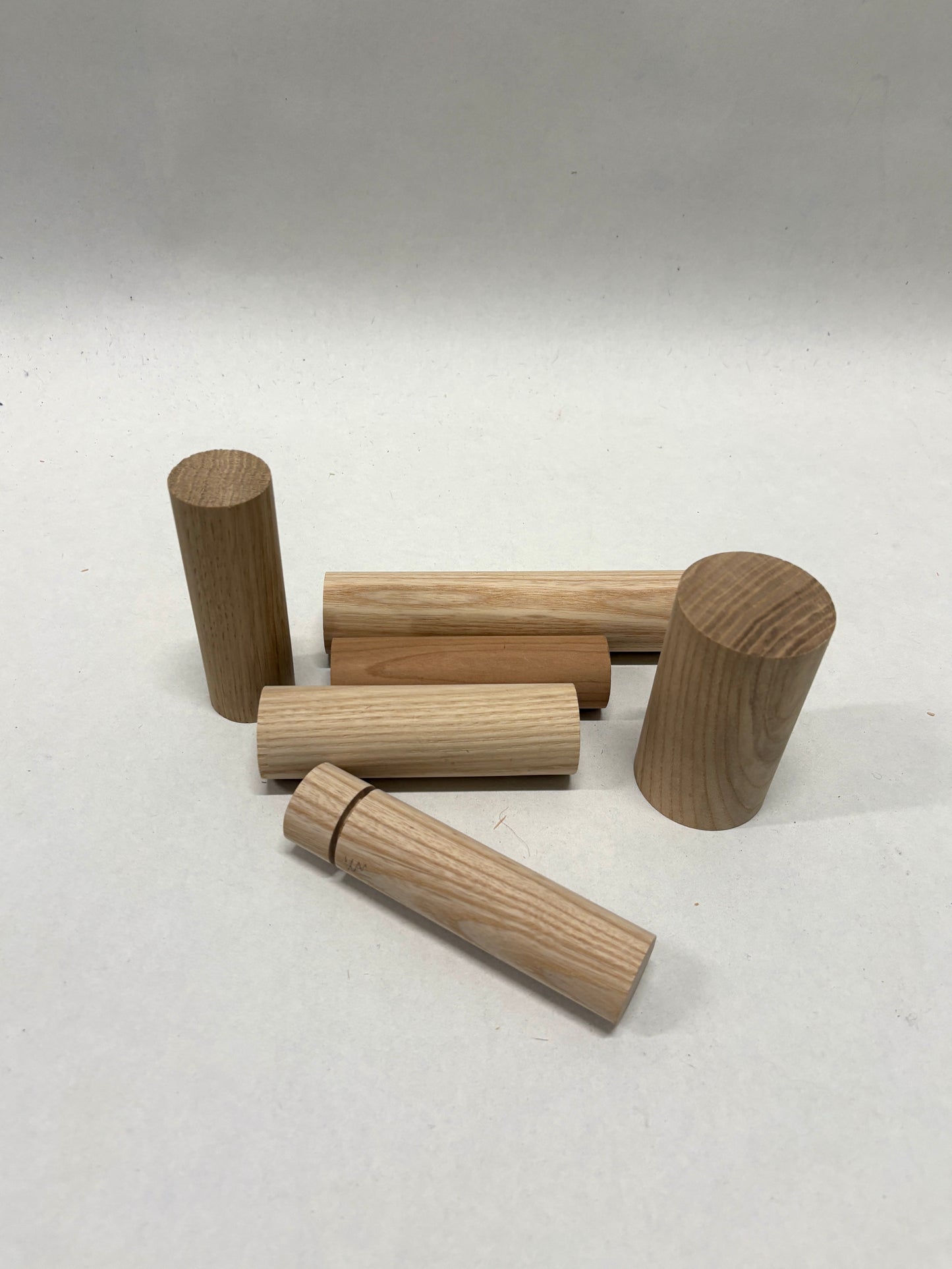 Collection of wooden dowels and cylindrical pieces on a white background.