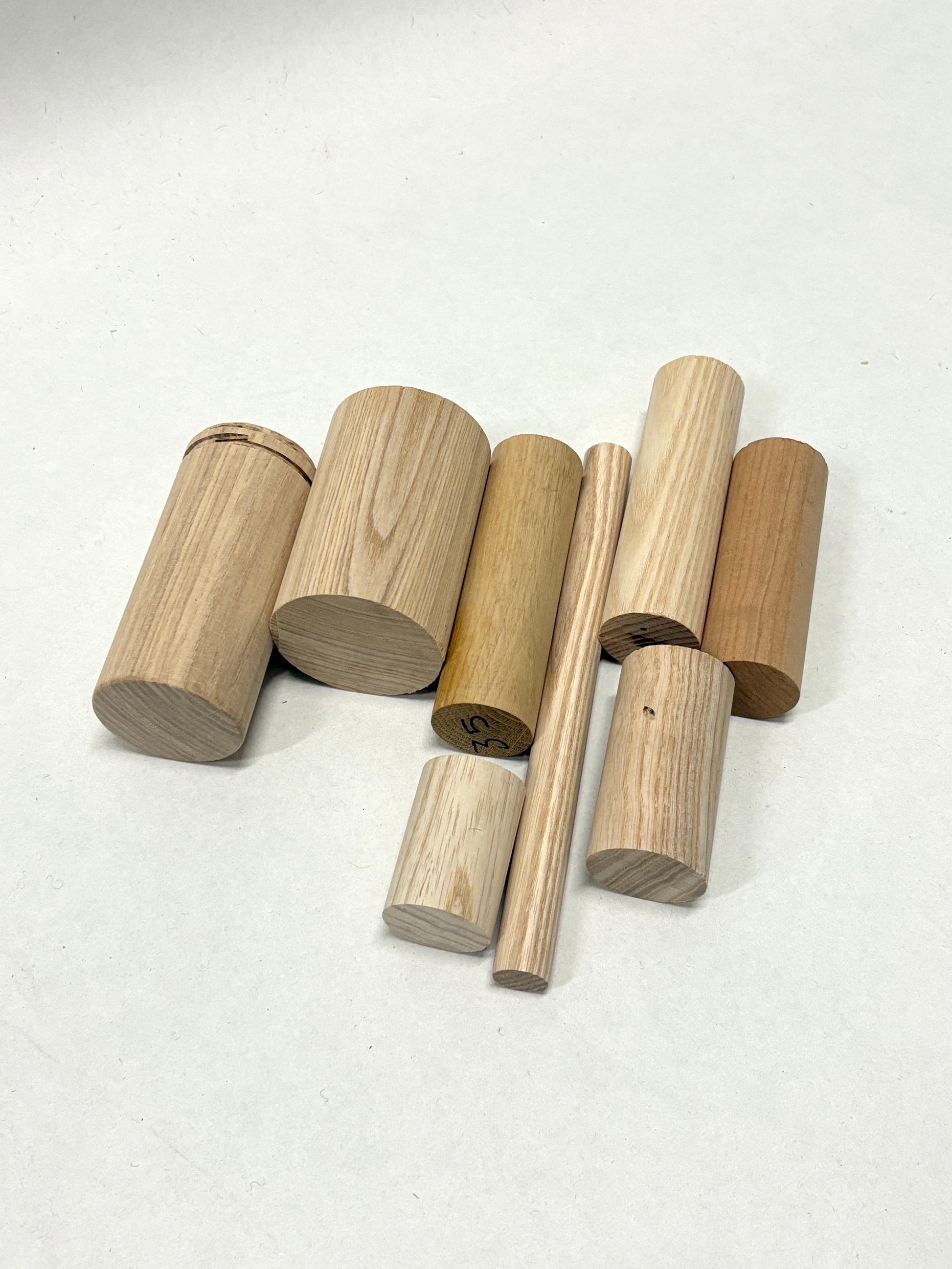 Assorted wooden rods and cylinder blocks arranged on a plain background.