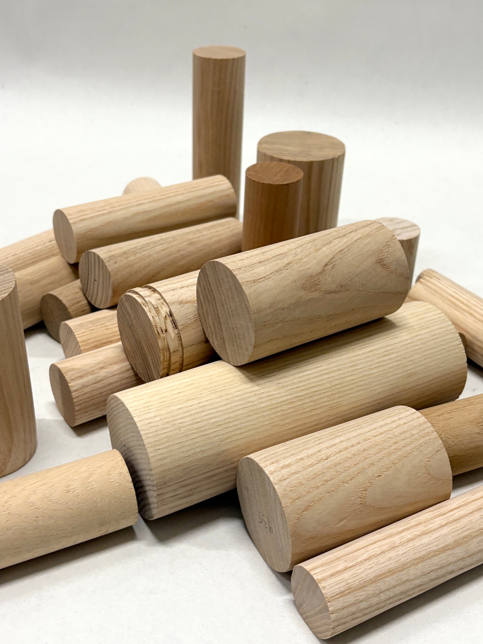 Various wooden cylinders and dowels laid out on a white surface.