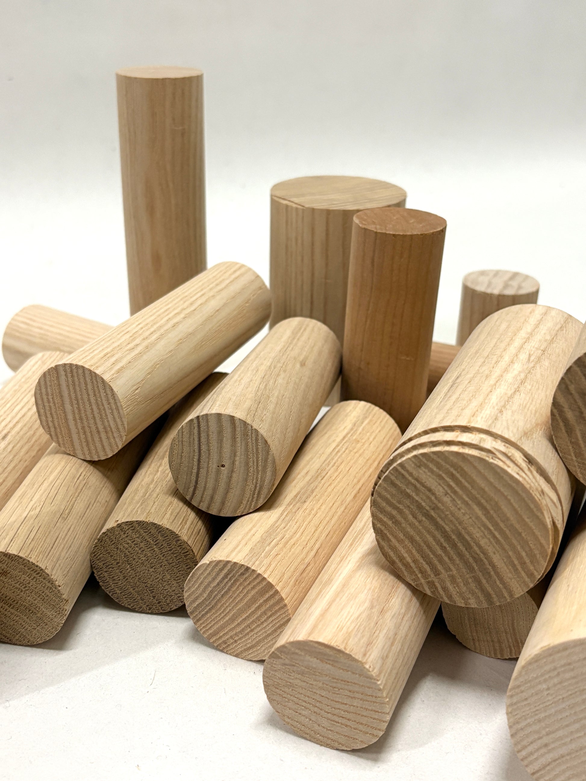 Selection of unfinished wooden dowels and cylindrical shapes on white.
