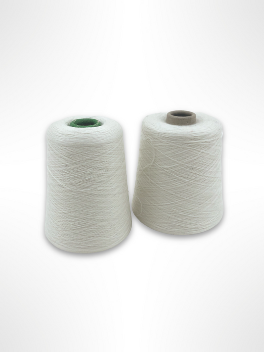 Two cones of white yarn, one made of blended cotton, wool, etc and the other of synthetic material, blended tencel, poly, etc, displayed against a white background.
